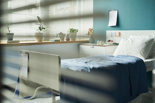 Hospital bed beside sunlit windows, creating a bright healthcare environment that supports patient comfort and recovery.