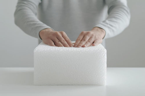 Woman pressing foam material to demonstrate its density, durability, and cushioning performance for industrial or commercial applications.