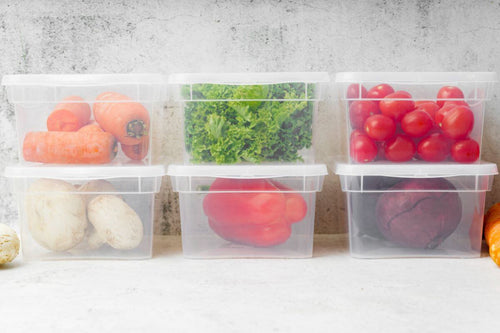 Clear food storage containers filled with vegetables on a kitchen counter
