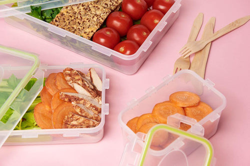 Plastic food containers holding prepared meals, vegetables, and bread for catering service